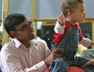 Therapist with a child in overalls on a red ball