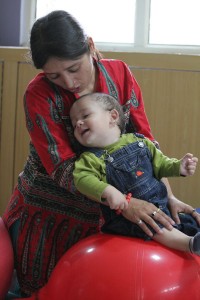 Teacher with child in blue jeans on a red ball