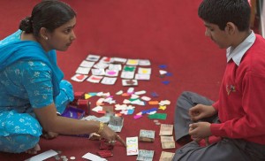 – Teacher and student sitting on the floor surrounded by study material