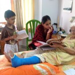 Elderly woman, leg in a cast, teaches children from her bed