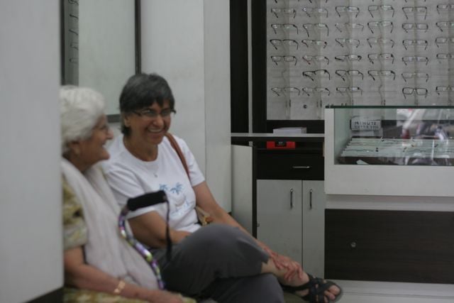 Woman sits with her mother in a spectacles shop
