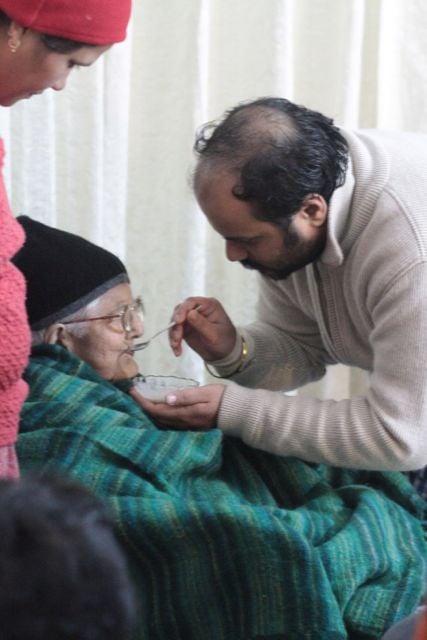 Young man feeds an elderly woman