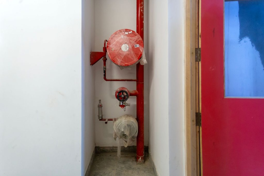 Picture of bright red fire fighting equipment agains a bright white wall in a building corridor