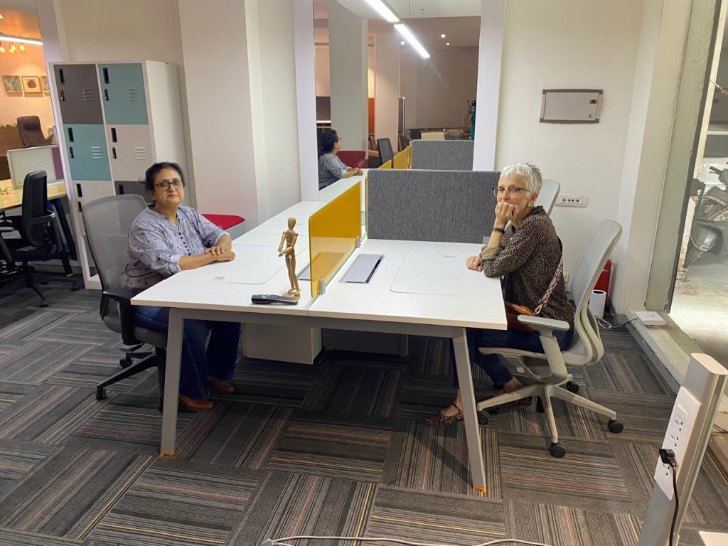Two women sitting at corporate looking desks in a furniture showroom