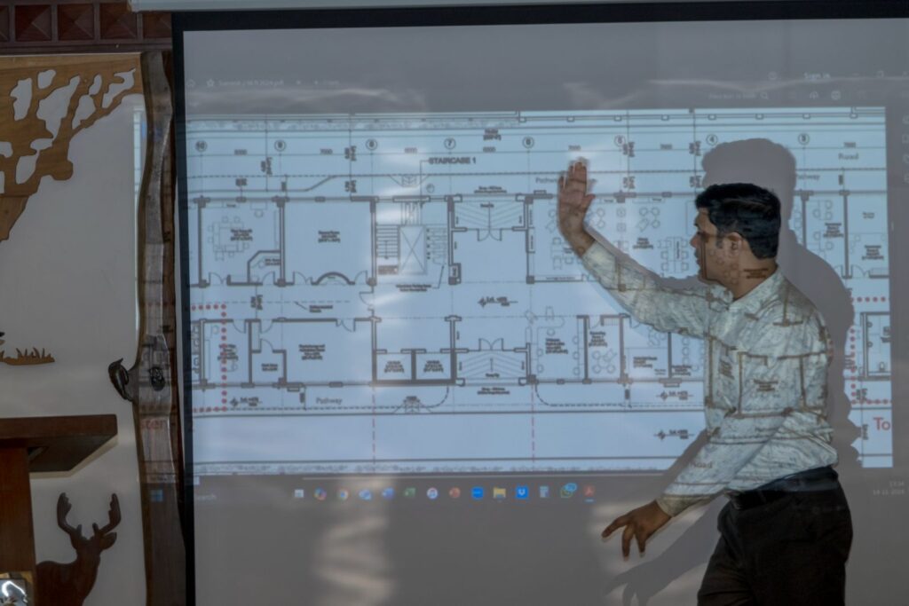 Subhash Chandra Vashishth gestures at a projected floor plan of the new Latika building during an accessibility review