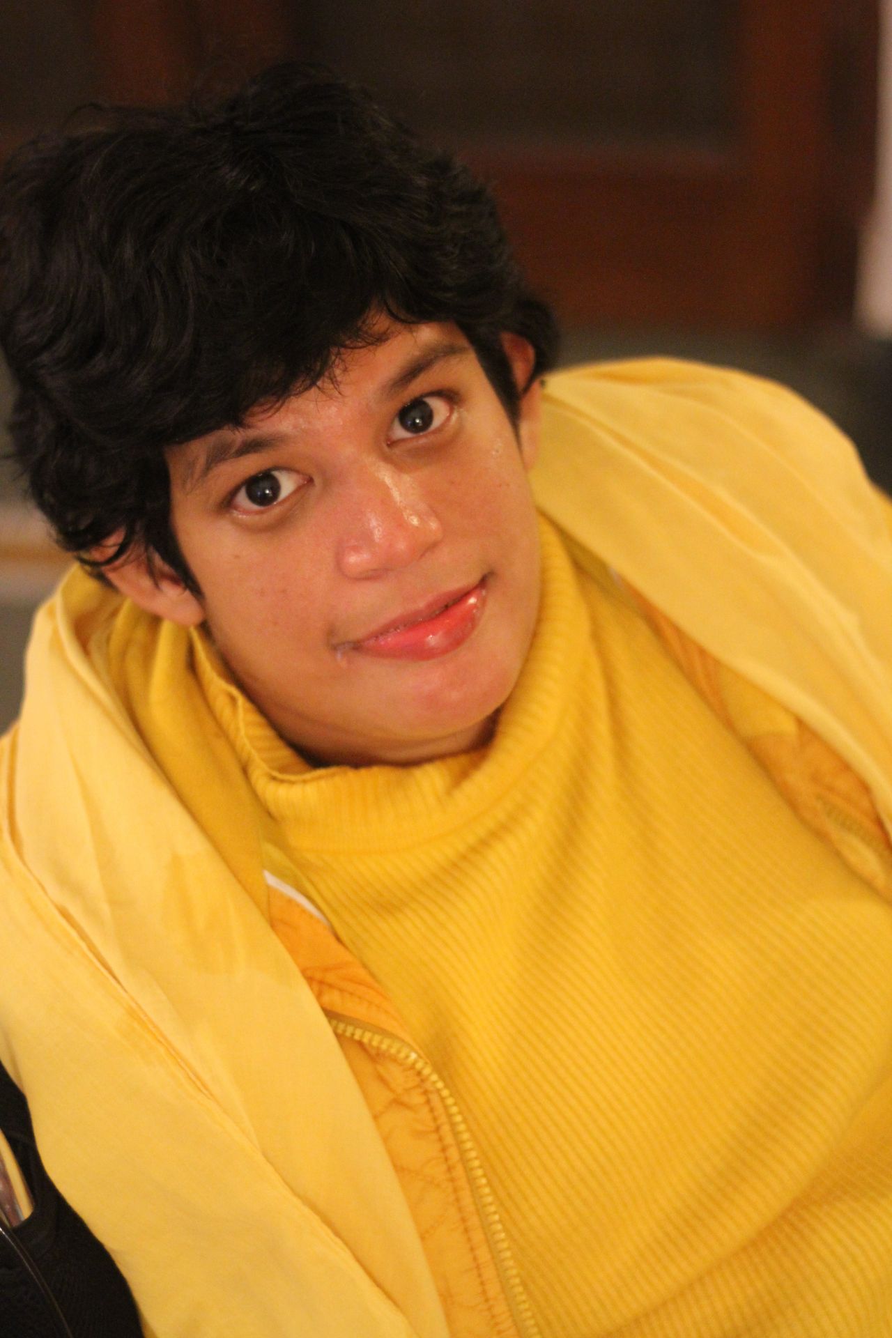 Close-up of Moy Moy as a teenager, draped in a sunny yellow turtleneck and matching hood