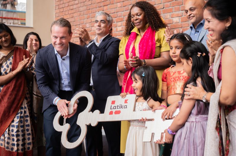 Dignitaries and Latika children hold an oversized wooden key with the Latika logo at the building handover ceremony