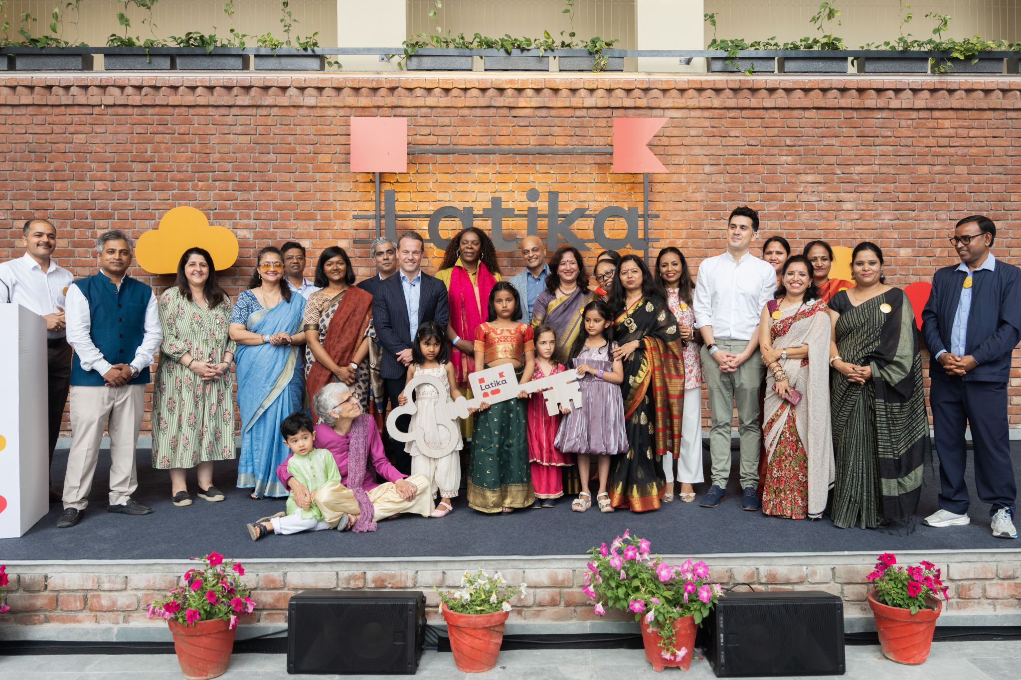 Group portrait of dignitaries and Latika children on stage at the building handover ceremony
