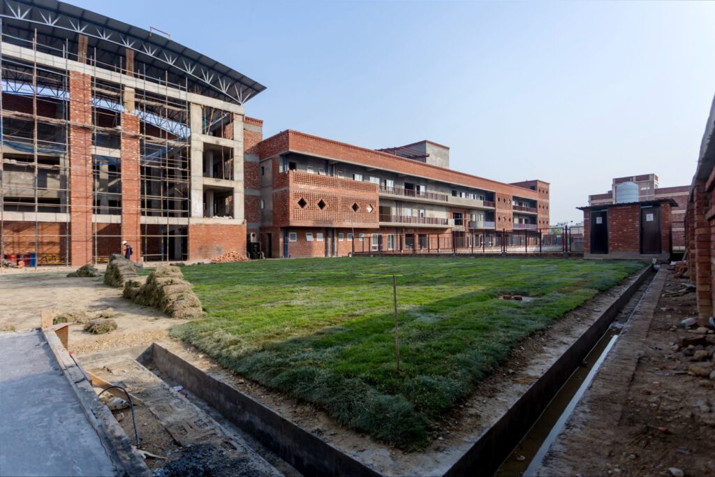 Wide exterior shot of the new Latika building under construction, surrounded by fresh lawn and an adjoining structure
