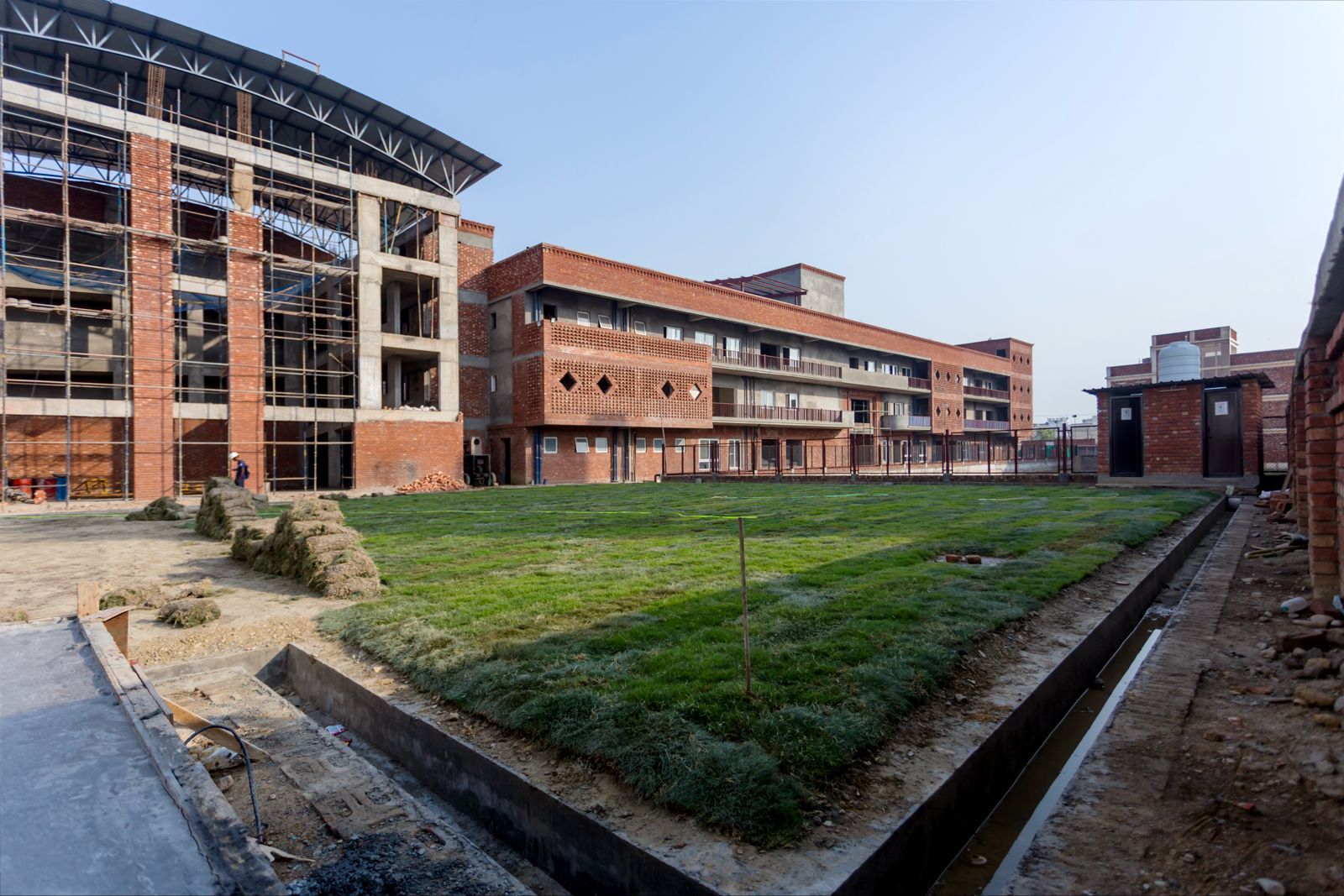 Wide exterior shot of the new Latika building under construction, surrounded by fresh lawn and an adjoining structure