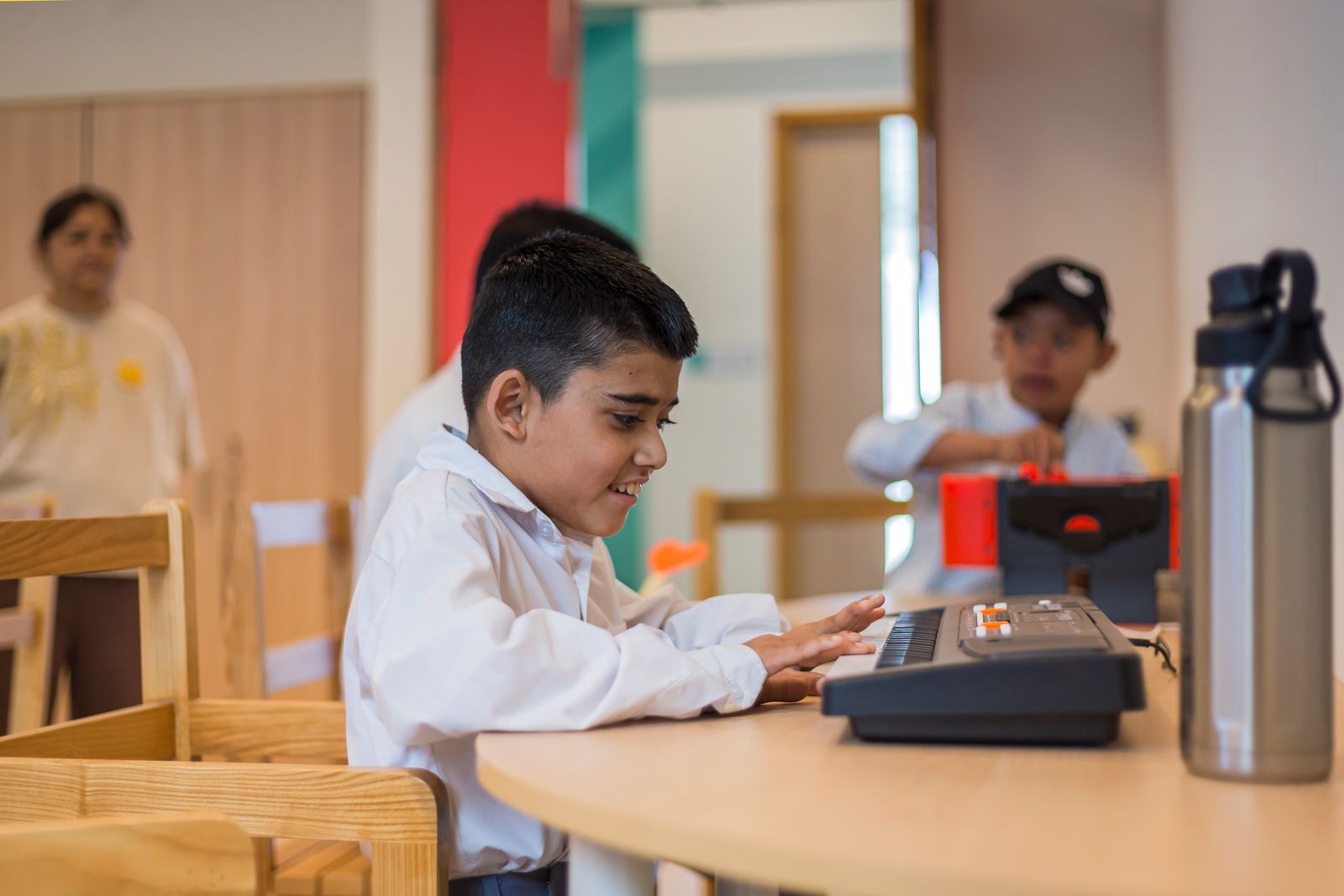 A young student concentrating on an electronic keyboard at a wooden table in the new building