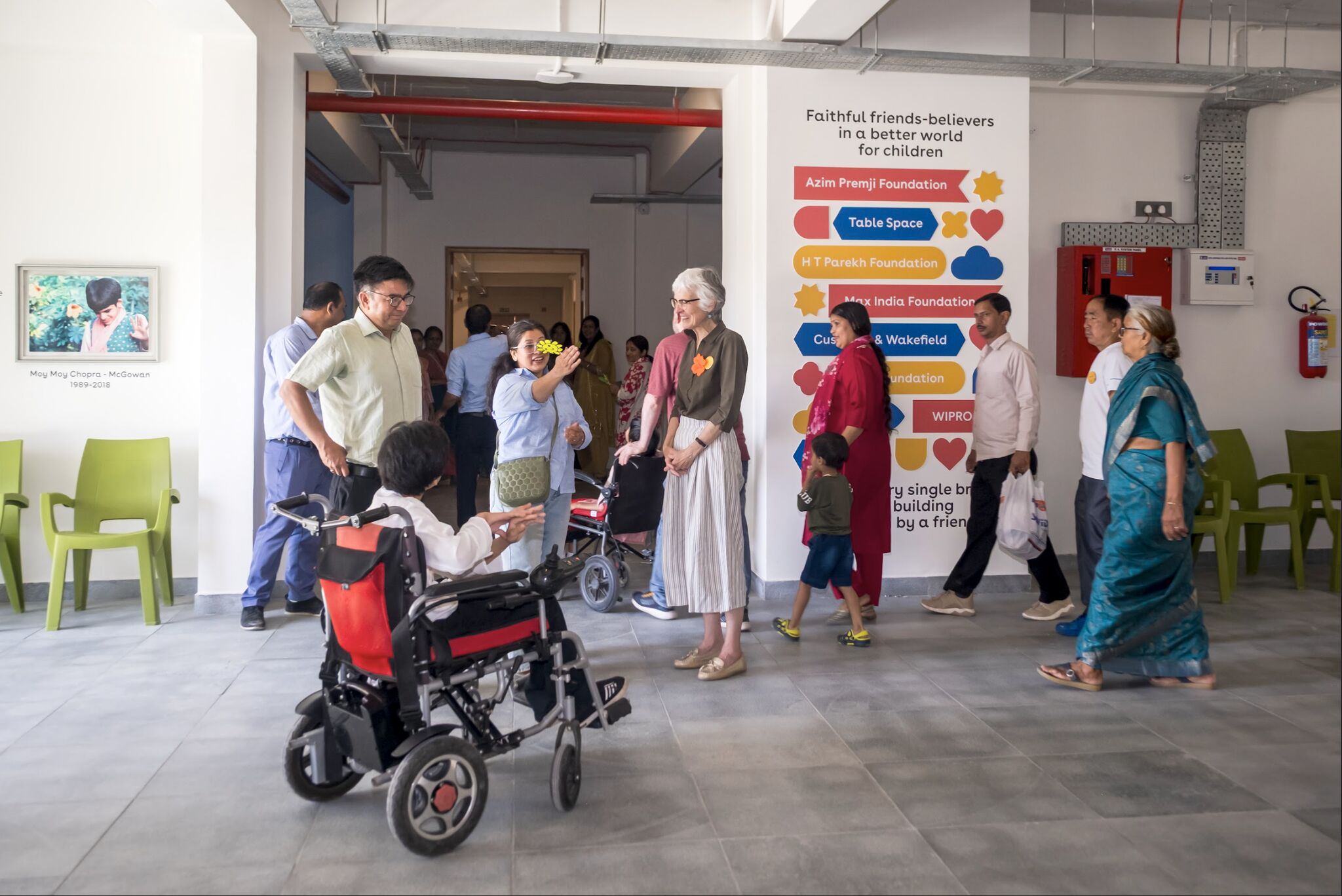 Open House visitors in the lobby beside the “Faithful friends-believers” donor wall, including a guest in a power wheelchair
