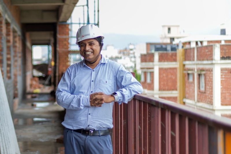 Ashish Rangari, project manager, smiling on a balcony of the under-construction Latika building