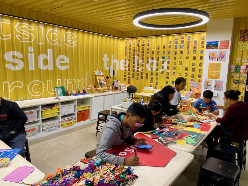 Children and adults making art together in the bright yellow studio at the Museum of Solutions in Mumbai