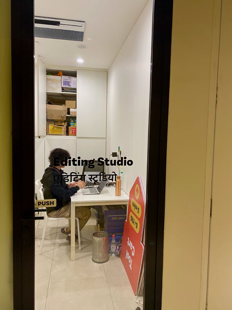 The Editing Studio at the Museum of Solutions — a young person working at a laptop in a small quiet room labelled in English and Hindi