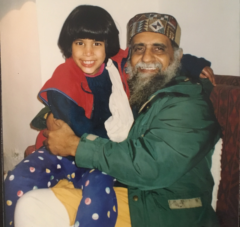 Vintage photo of a smiling Moy Moy with bobbed hair being held by a bearded man in a green jacket and Himachali cap
