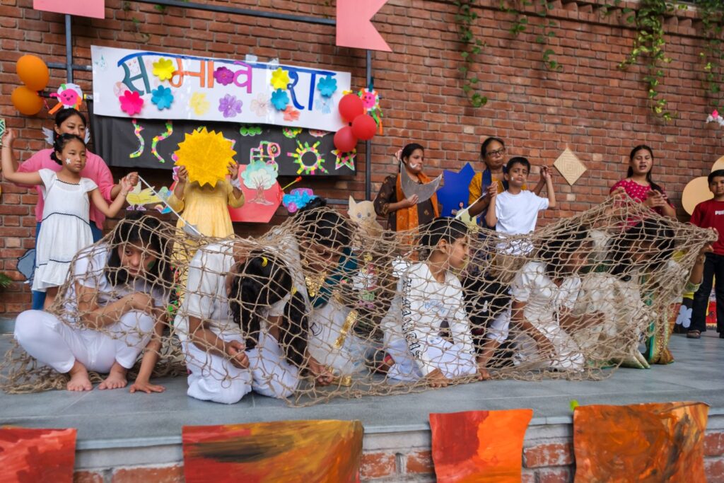 Children dressed in white crouch under a jute net during the Na Kaato Mujhe dance about protecting nature