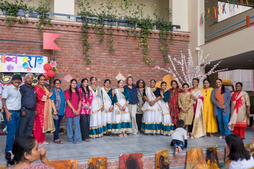 Latika parents and performers, some in matching white and teal dance costumes, lined up together on the Samavesh stage